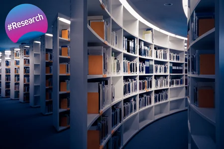 A modern library with curved bookshelves filled with books and documents, creating a visually appealing and organised space for reading and studying. There is a #Research badge on the top left corner.