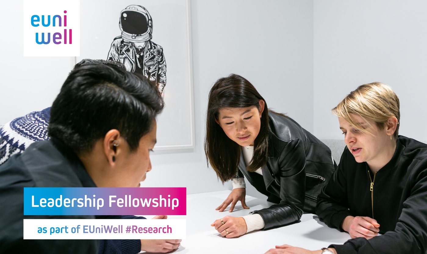 Four people working together at a table. In the upper left corner is the EUniWell logo, in the lower part of the picture stands the text: "Leadership Fellowship as part of EUniWell #Research".