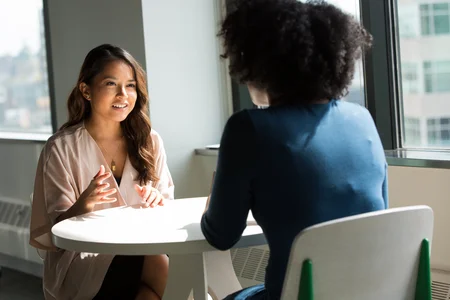 Two women sitting at a table having a casual conversation.