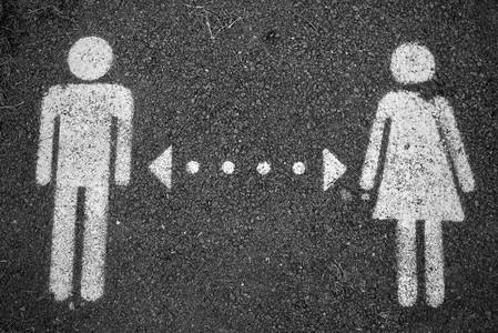 A graphic representation symbolising gender inequality between men and women. The image features white pictograms of a man and a woman on a black, textured background, separated by a divisional arrow.