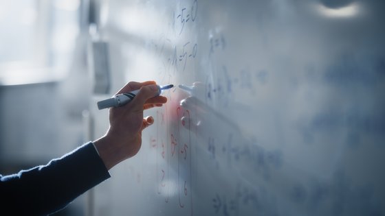 Bright photo of a hand writing on a whiteboard with a marker pen