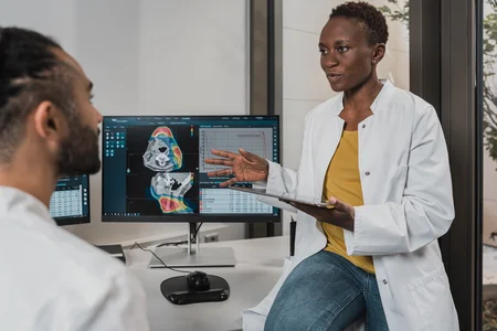 Two individuals in a medical setting, with one person holding a tablet with medical images.