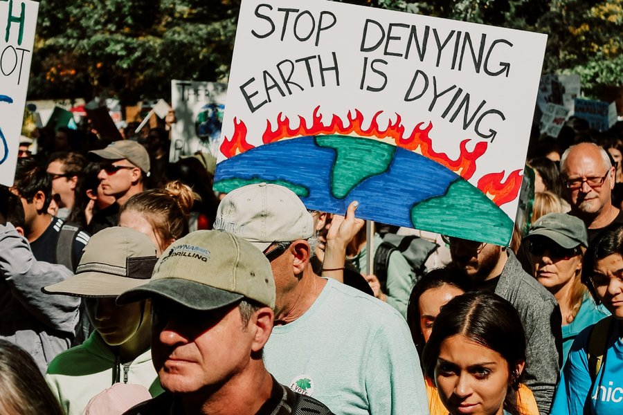 People protesting with a sign that reads "Stop denying - Earth is dying".