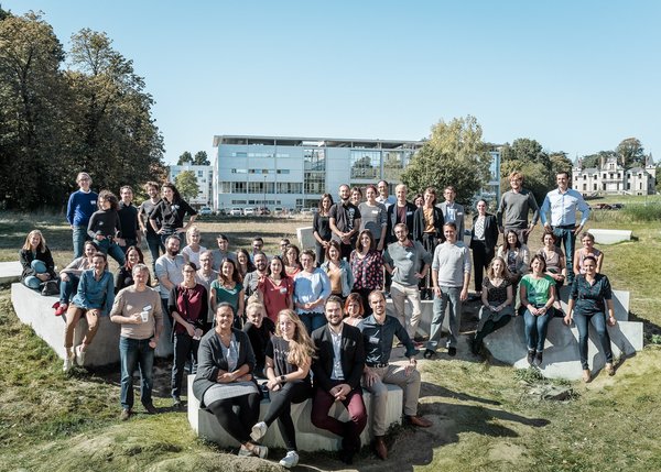 The photo shows a large group of students and staff from the University of Nantes. They are grouped on an array of concrete blocks on a lawn. Trees and two buildings can be seen in the background.