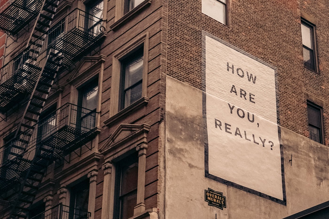A brick building with a big sign reading "How are you, really?"