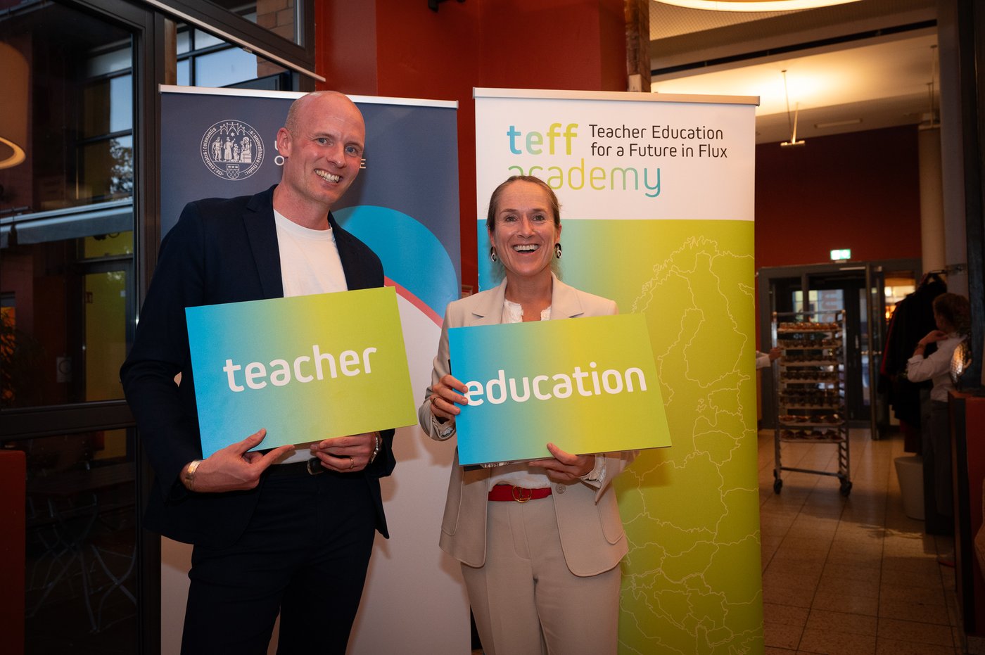 Two people holding signs with the words "teacher" and "education", suggesting a focus on educational themes or initiatives.