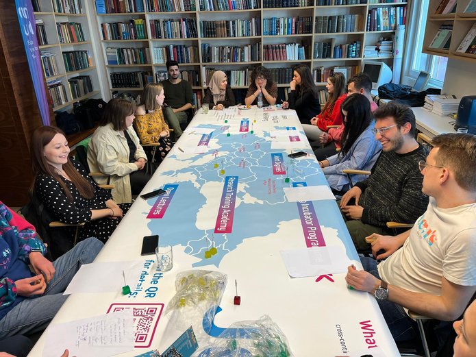 A group of students sits around a long table on which the EUniWell map is spread out.