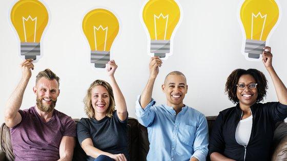 Picture of 4 people smiling and holding signs shapped as light bulbs
